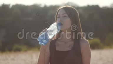 小可爱的女人在炎热的夏天从大自然中的塑料瓶里<strong>喝水</strong>。 女孩渴望<strong>喝水</strong>